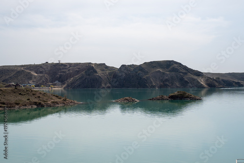 Solitary lighthouse on a pier surrounded by turquoise water. Qonayev, Central Asia