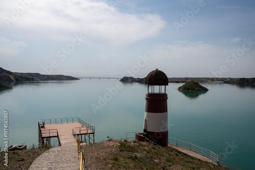 Solitary lighthouse on a pier surrounded by turquoise water. Qonayev, Central Asia
