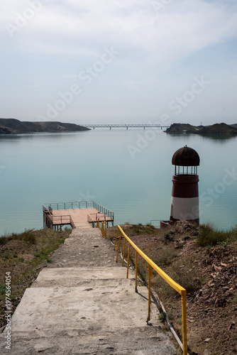 Solitary lighthouse on a pier surrounded by turquoise water. Qonayev, Central Asia