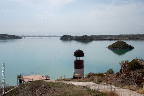 Solitary lighthouse on a pier surrounded by turquoise water. Qonayev, Central Asia