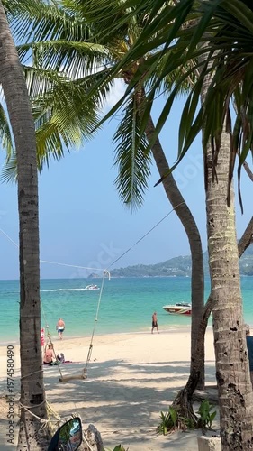 Scenic view of Patong beach on Phuket island, Thailand. Tropical sea landscape with coconut palm trees, white sand, turquoise water and boats under blue sky during sunny summer vacation.