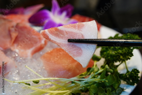 close-up photo of a piece of fresh tuna sashimi picked up with chopsticks.