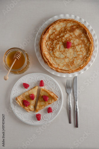 Breakfast crepes with honey and raspberries, top view.
