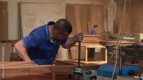 Footage of a carpenter adjusting a woodworking machine before production. Shows setup, calibration, and hands-on control in a professional workshop environment.
