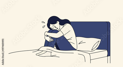A sad young woman sits crying and curled up on her bed in a state of distress