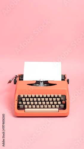 A retro orange typewriter sits centered against a solid pink backdrop. A blank white sheet of paper is loaded