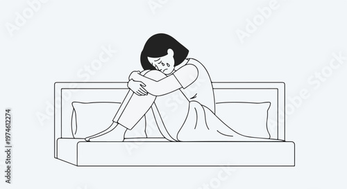 A sad young woman sits crying on a bed with her knees pulled to her chest