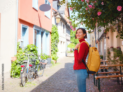 Tourist woman enjoys historic charm of Hochst near Frankfurt, wandering through picturesque streets with old houses and cobblestone alleys, soaking in peaceful atmosphere of old town.