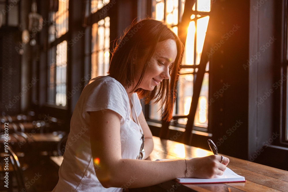 Naklejka premium Woman writing in sunlight.