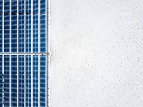 Aerial shot showing a line of solar panels next to a cracked, dry white surface.