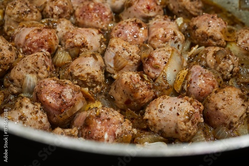 Pieces of pork sausage frying in a skillet