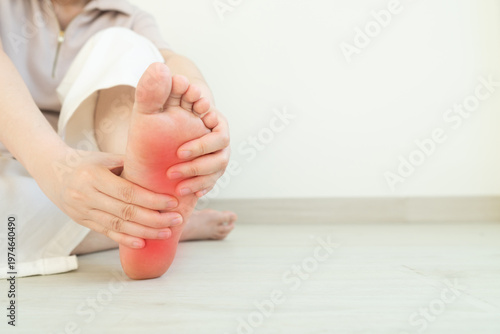 Female suffering from foot pain or numbness at home. Causes of pain include plantar fasciitis, gout, arthritis, tendinitis, diabetic neuropathy or overuse injuries.