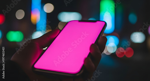 Hand holding smartphone with bright pink screen at night city background