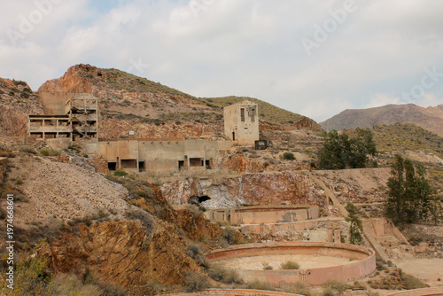 An expansive view of the desolate and arid surroundings of the abandoned Rodalquilar gold mines in Almeria. The image showcases the decaying industrial plant surrounded by dry volcanic hills