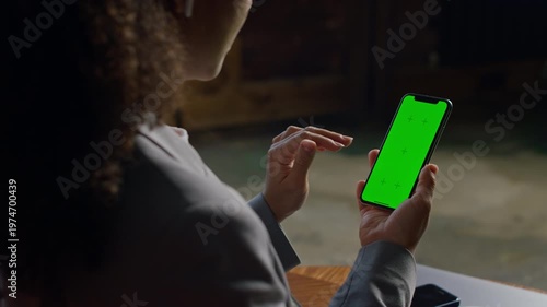 Woman tapping green screen smartphone indoors
