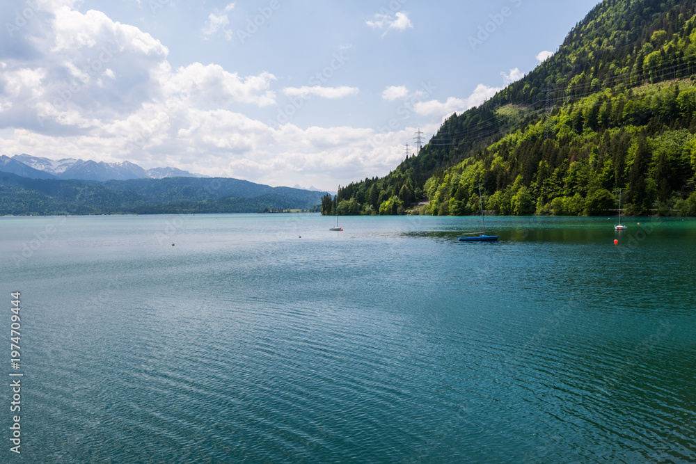 Obraz premium Panoramic view of turquoise Lake Walchensee and the Bavarian Alps under a cloudy sky