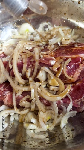 Adding Soy Sauce to Pork Meat and Onions for Barbecue in a Large Metal Bowl