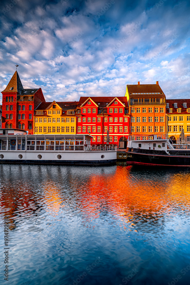 Obraz premium Vertical photo traditional colorful buildings of Nyhavn in Copenhagen at sunrise with boats, Denmark