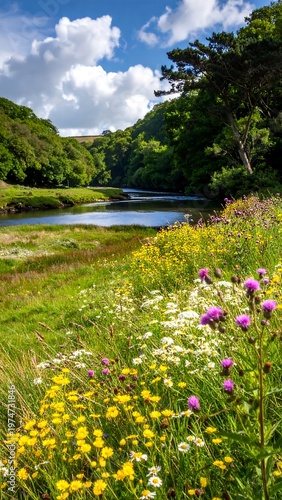 A serene river flows through a vibrant meadow, flanked by lush green trees and a partly cloudy blue sky