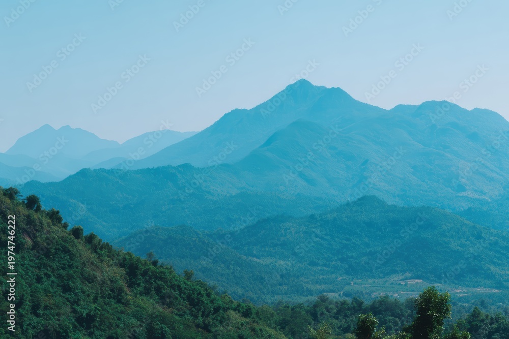 Fototapeta premium 緑の丘の上に青い空に山々がそびえ立つ