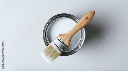 Painting tools with white paint can and paintbrush on a neutral surface, showing home improvement, renovation, and creative hobby concepts, diy work
