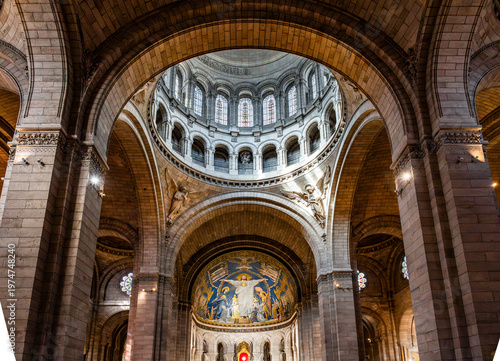 Fotografie Interior view of the Basilica of the Sacred Heart of Montmartre showing the central dome with mosaics, the nave and colored stained glass windows in warm light, in Paris, France