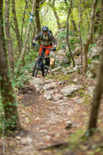 Mountain biking cyclist navigating a rocky forest trail on an electric mountain bike during outdoor adventure