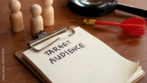 Target Audience list on clipboard with magnifying glass and wooden figures for market segmentation