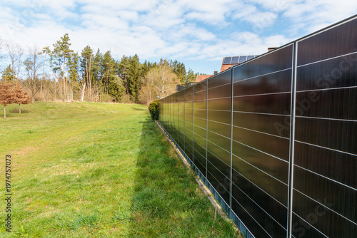 Vertical solar panel fence generating renewable energy along residential property boundary, modern photovoltaic system, sustainable technology, clean power solution