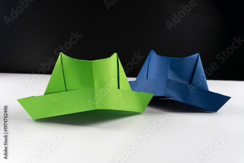 colorful origami paper hats in a row on a white surface.