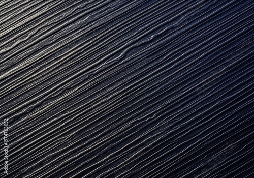 Detailed macro photograph of rough, dark plastic surface featuring deep, textured furrows, useful as an industrial background element, texture, plastic, grooved