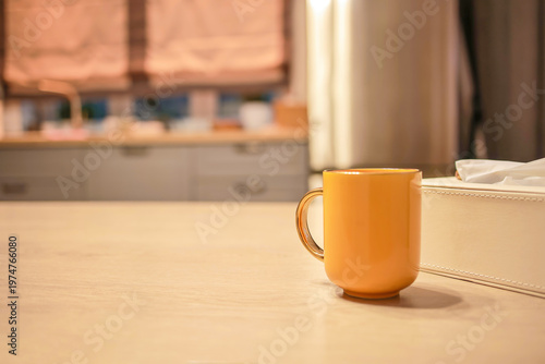 Tableau sur toile A yellow ceramic mug stands on a light table in the kitchen