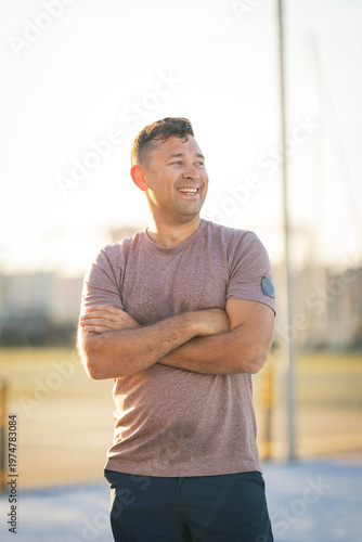 Smiling man with arms crossed looking away outdoors