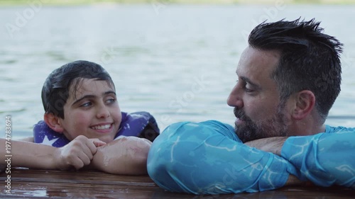 Wallpaper Mural A boy and his father rest their arms on a pier and laugh as they're still in the water. Torontodigital.ca