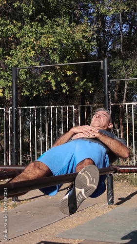 Athletic Middle Aged Man Doing Crunches on Parallel Bars - Calisthenics Park - Street Workout. Series Track Code: Fit-Mature-Man-54-Outdoor-Fitness-Series-2024