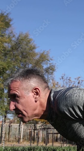 Athletic Middle Aged Man Doing Pushups Outdoors. 54-year-old Man Workout on Grass Field. Series Track Code: Fit-Mature-Man-54-Outdoor-Fitness-Series-2024