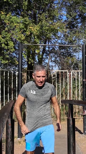 Strong Senior Male Doing Parallel Bar Dips - Calisthenics Park - Street Workout. Series Track Code: Fit-Mature-Man-54-Outdoor-Fitness-Series-2024