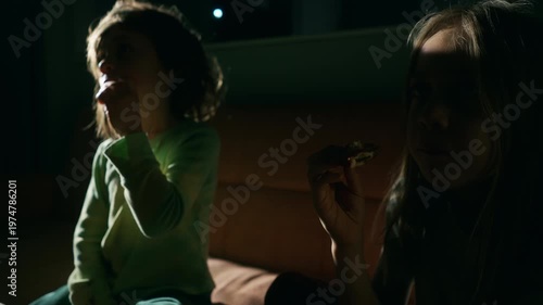 Two boys watching a movie on the sofa in the dark