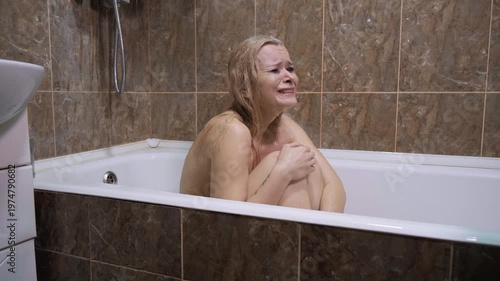 Psychological breakdown, inner conflict, loneliness or abusive relationship. Blonde woman crying in bathtub, mascara stains, wet tears, sad distant gaze, bathroom, closeup despair, emotional state