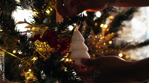 Person hanging christmas tree ornament during holidays