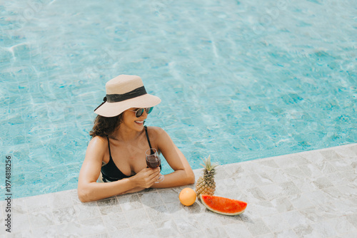 Young beautiful woman in black bikini wearing hat and sunglasses relaxing in swimming pool. Caucasian female in swimwear chilling in pool. Summer vacation concept.