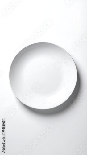 A stark white, circular plate rests on a white background, lit with soft, even light. The dish is empty, showcasing its clean design