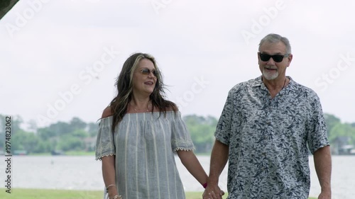 Wallpaper Mural An older man and woman walk along the water's edge at a lake as they hold hands and smile. Torontodigital.ca