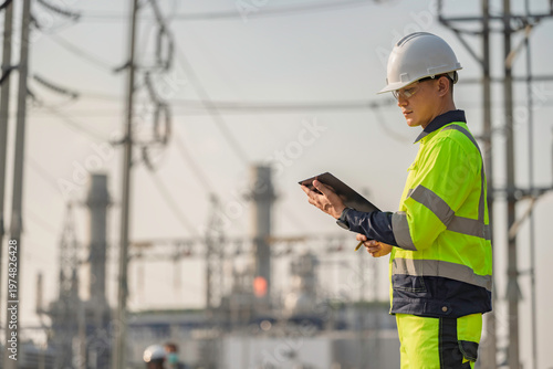 Foto Asian male electrical engineer holding digital tablet standing at power plant station