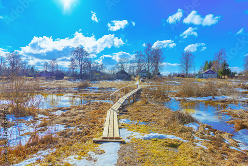 Spring flood in a traditional Russian village with a wooden footbridge.Problems of flooding and inundation of populated areas, emergency situation.