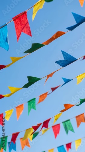 Colorful Festa Junina pennant flags strung against a clear blue sky