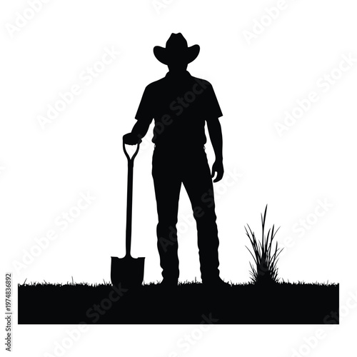 Silhouette of a male farmer wearing a cowboy hat holding a shovel standing in a field with grass and a patch of taller grass with his body in a relaxed stance