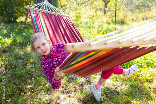 Girl Enjoys Swinging in a Hammock Outdoors During a Sunny Day in a Garden Setting