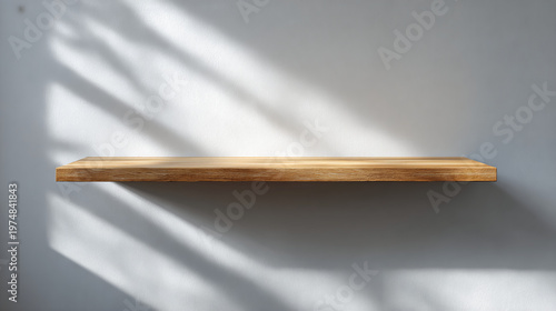 A minimalist wooden shelf casts soft shadows on a smooth wall, showcasing a simple yet elegant design.
