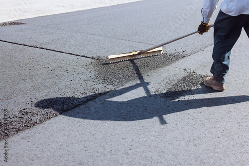 Foto Worker levels asphalt on road reconstruction site during parking lot renovation using rake tool
